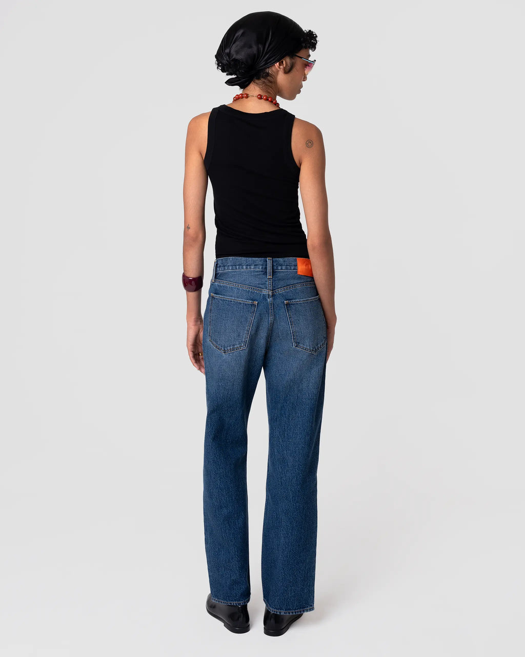 Rear view of Oketo Cut 101 Straight Jean—vintage indigo, dark wash, straight leg, mid-rise, structured drape, orange patch at back.
