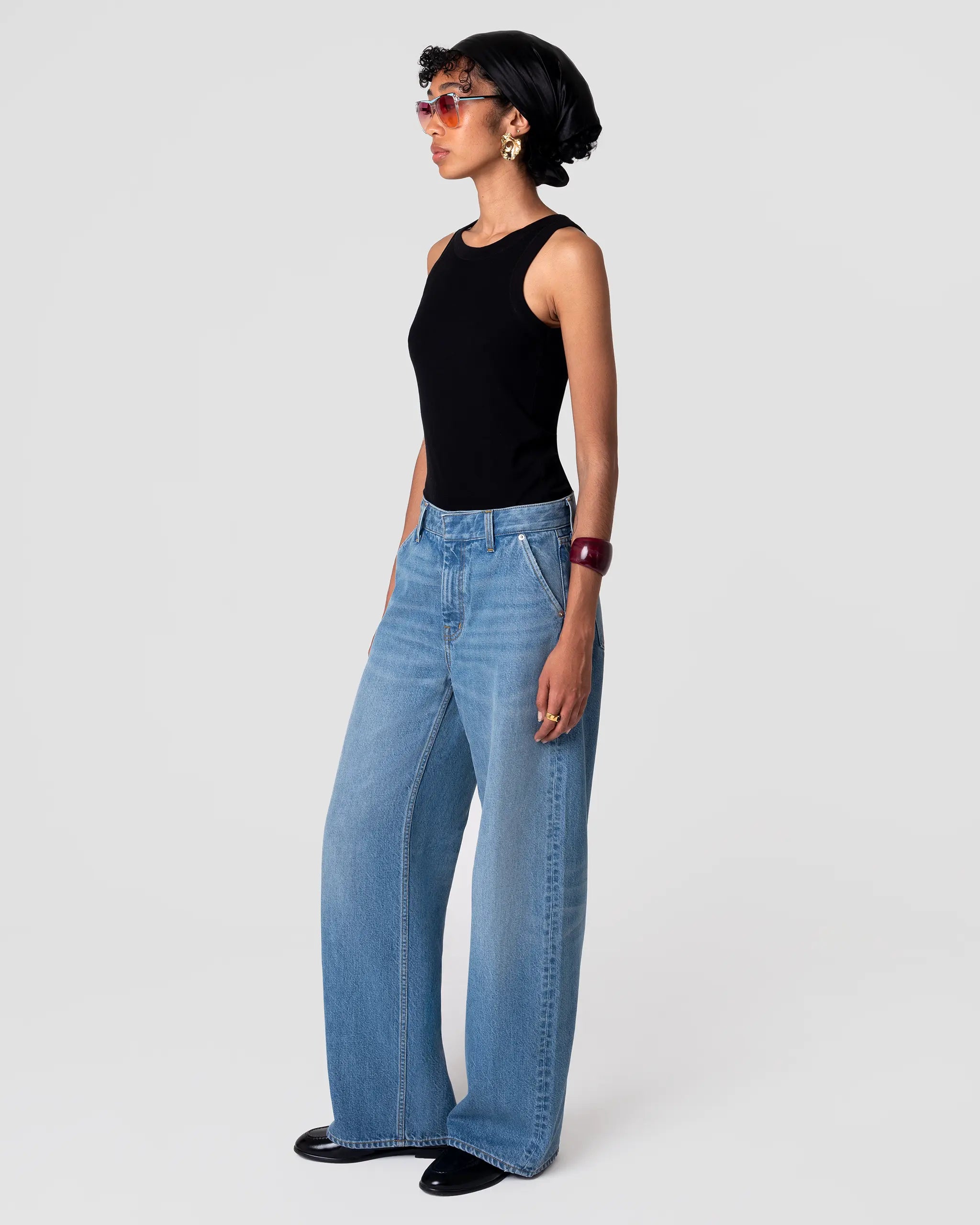 Oketo Cut 102 Tailored Jean in Vintage Light, mid-rise, structured leg, subtle fading; shown with black top. Hands in pockets.