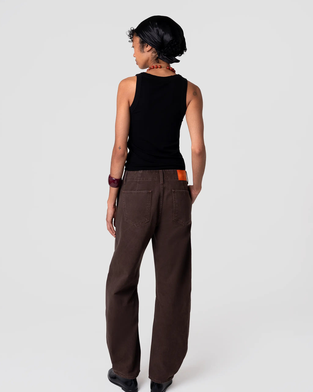Rear view of Cut 103 Barrel Jean in Espresso: mid-rise, loose fit, generous leg, soft matte twill, minimal surface detail. Pleated hem detail at cuff adds volume.
