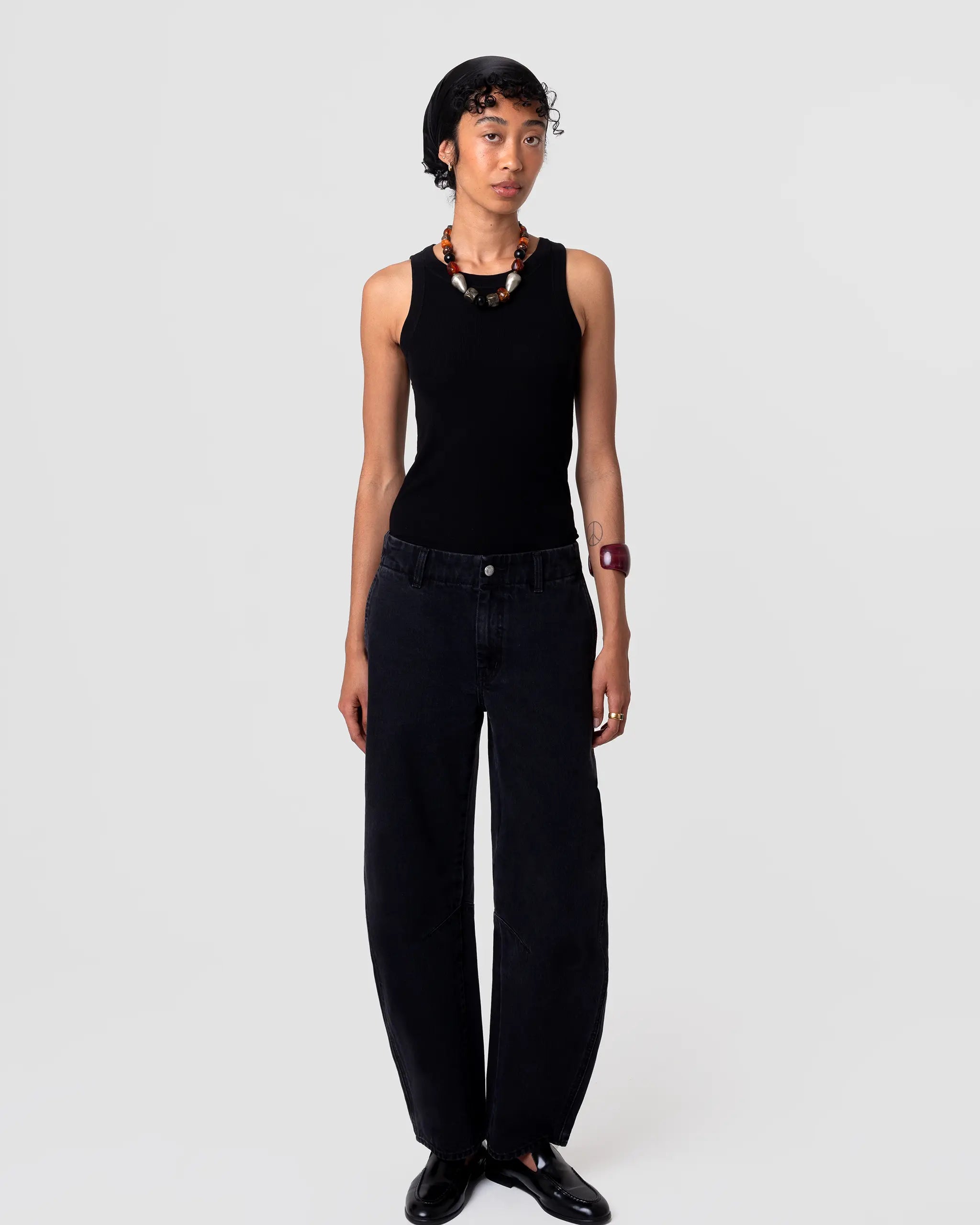 Cut 103 Barrel Jean in deep black denim; structured, voluminous leg; cropped, mid rise, slight taper. Matte finish. Front view. Pleated hem detail at cuff adds volume.