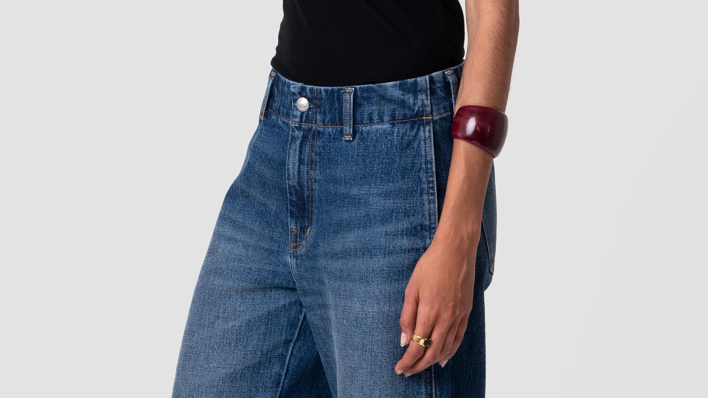 High-rise blue jeans with a tapered leg, deep indigo wash, subtle fading; shown on model from waist to mid-thigh, front view.